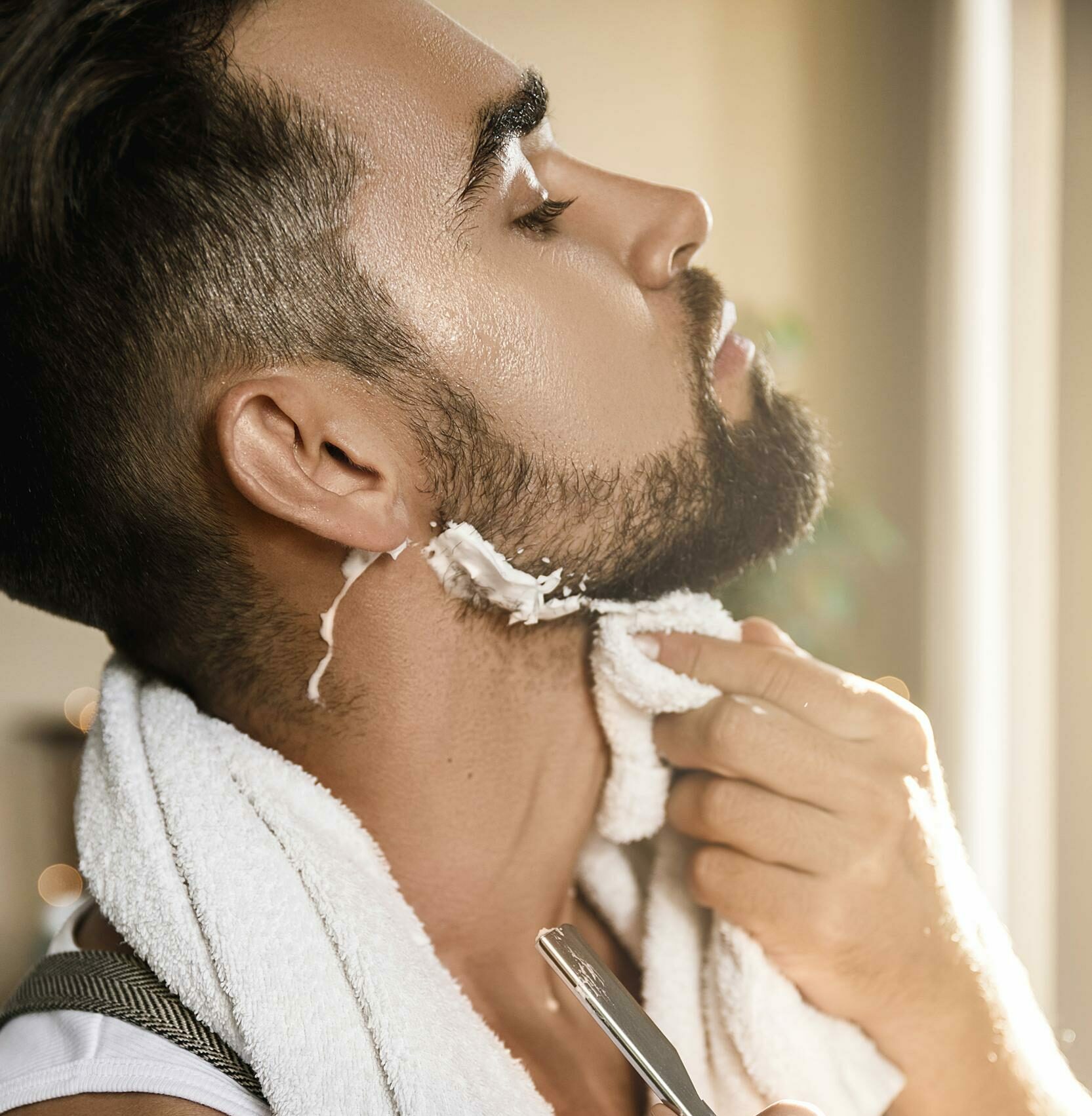 hombre afeitandose la barba con una navaja de afeitar recta