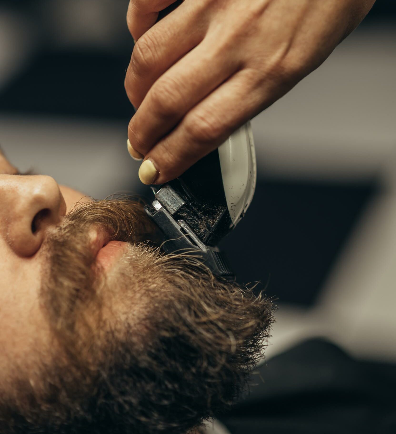 joven barbudo recibiendo corte de pelo de barba por peluquero