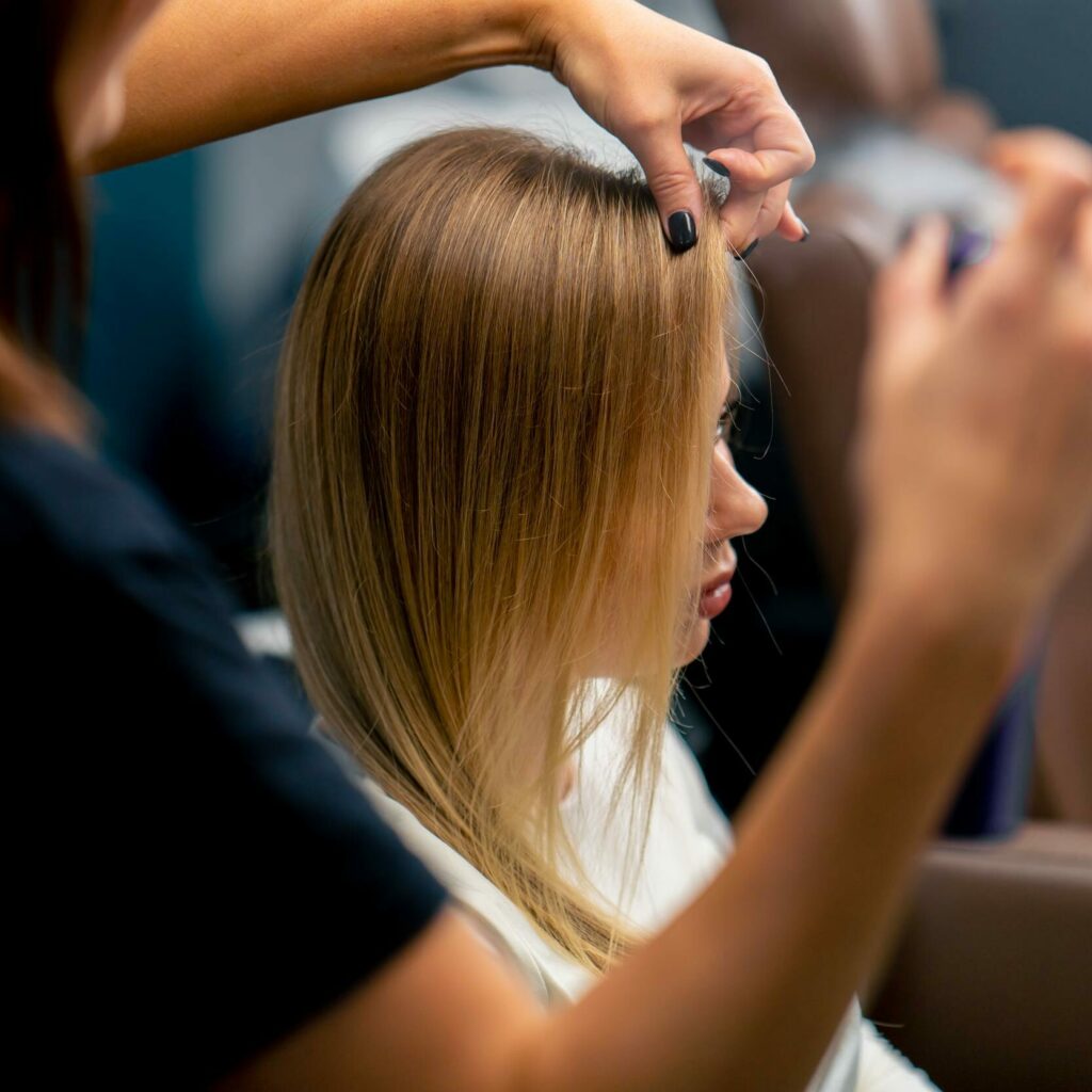 peluquero rocia laca en el cabello del cliente