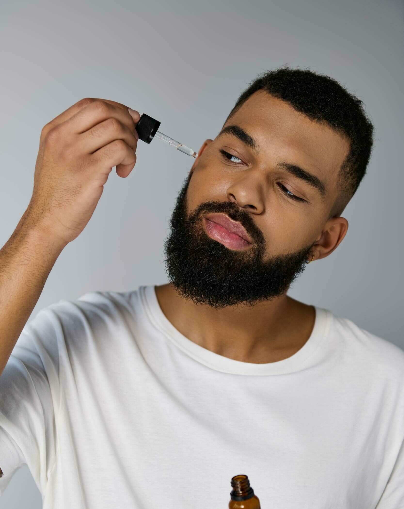 Un joven guapo con barba sosteniendo una botella de aceites esenciales