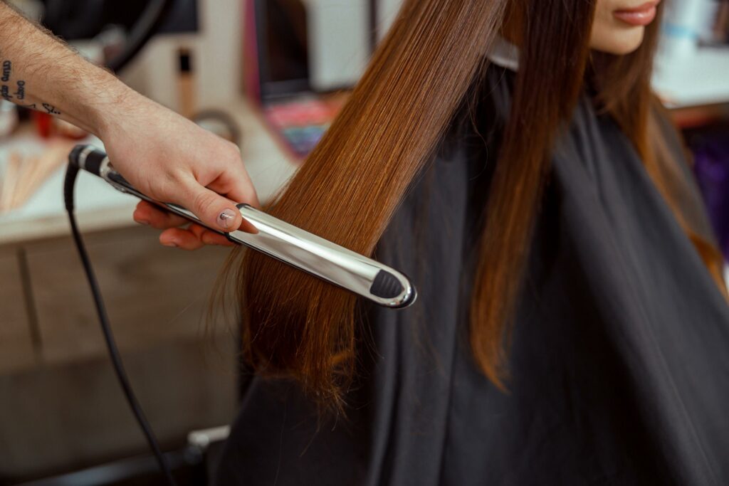 primer plano de la mano del peluquero sujetando la plancha de pelo