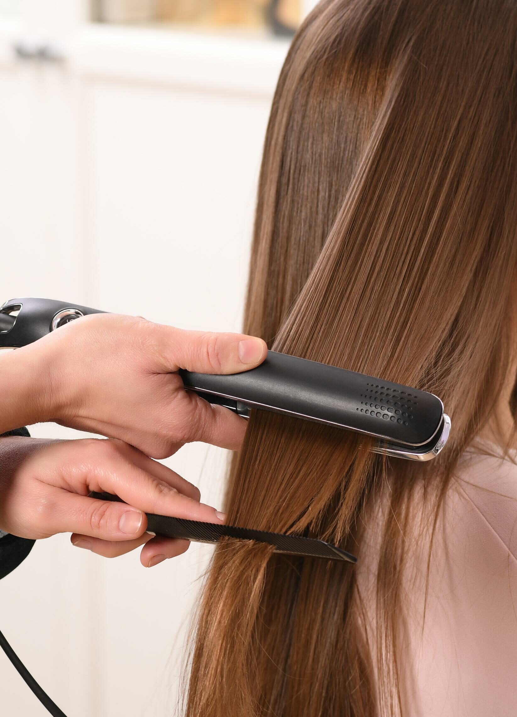 una mujer usa una plancha de pelo en peluqueria