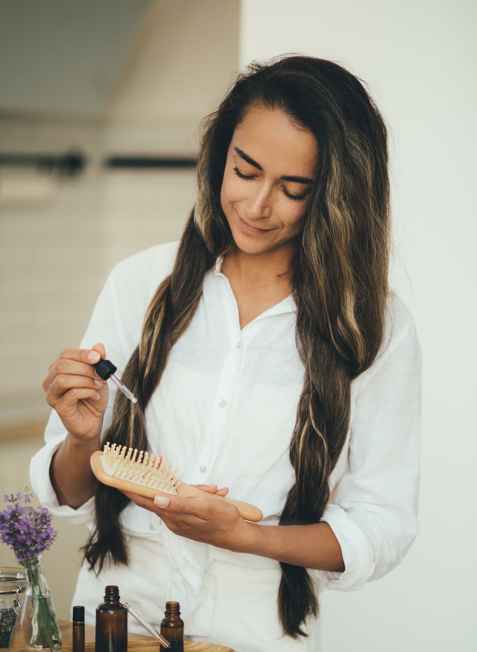 mujer aplicando aceite esencial orgánico natural sobre cepillo de madera