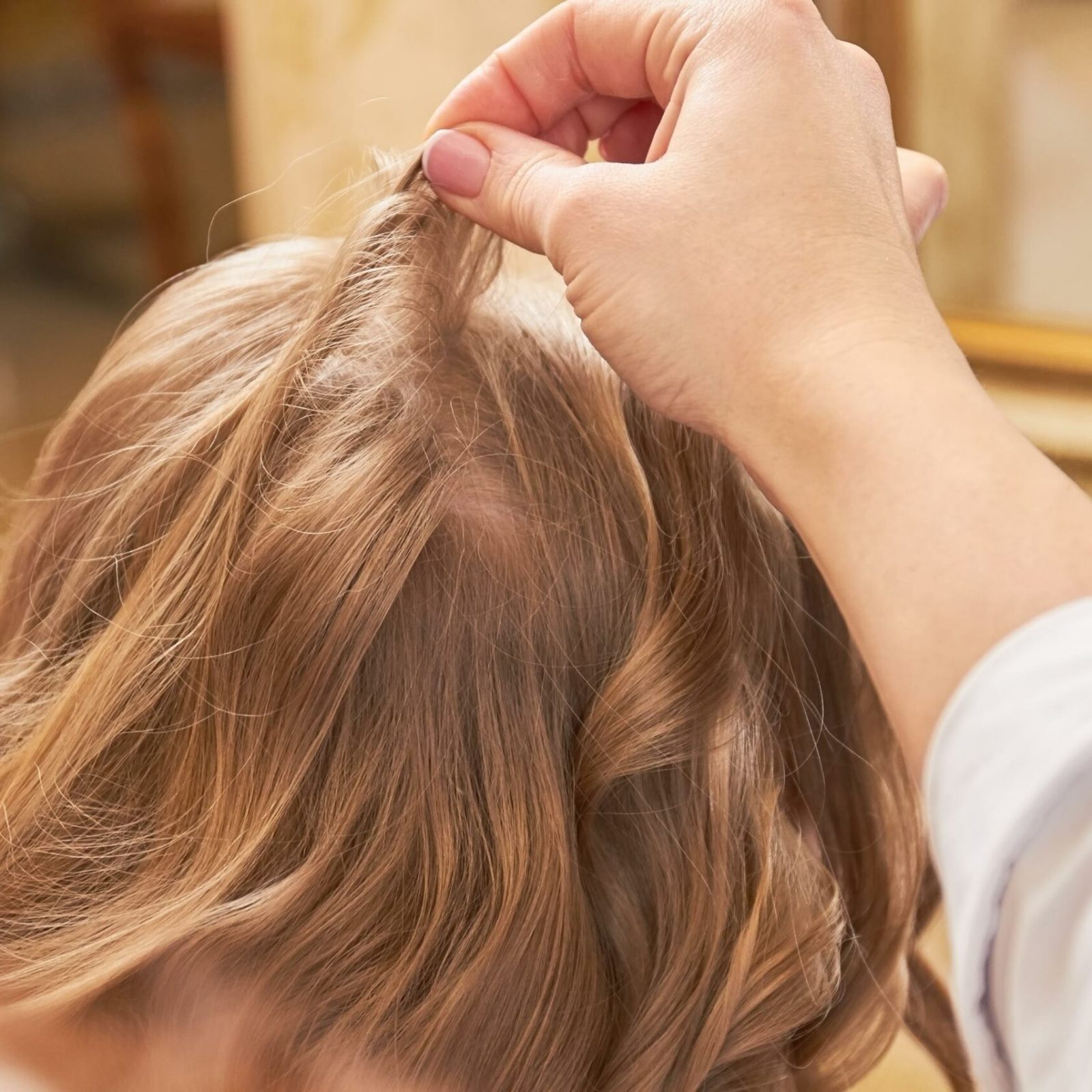 Mano de una peluquera. Primer plano de cabello rubio