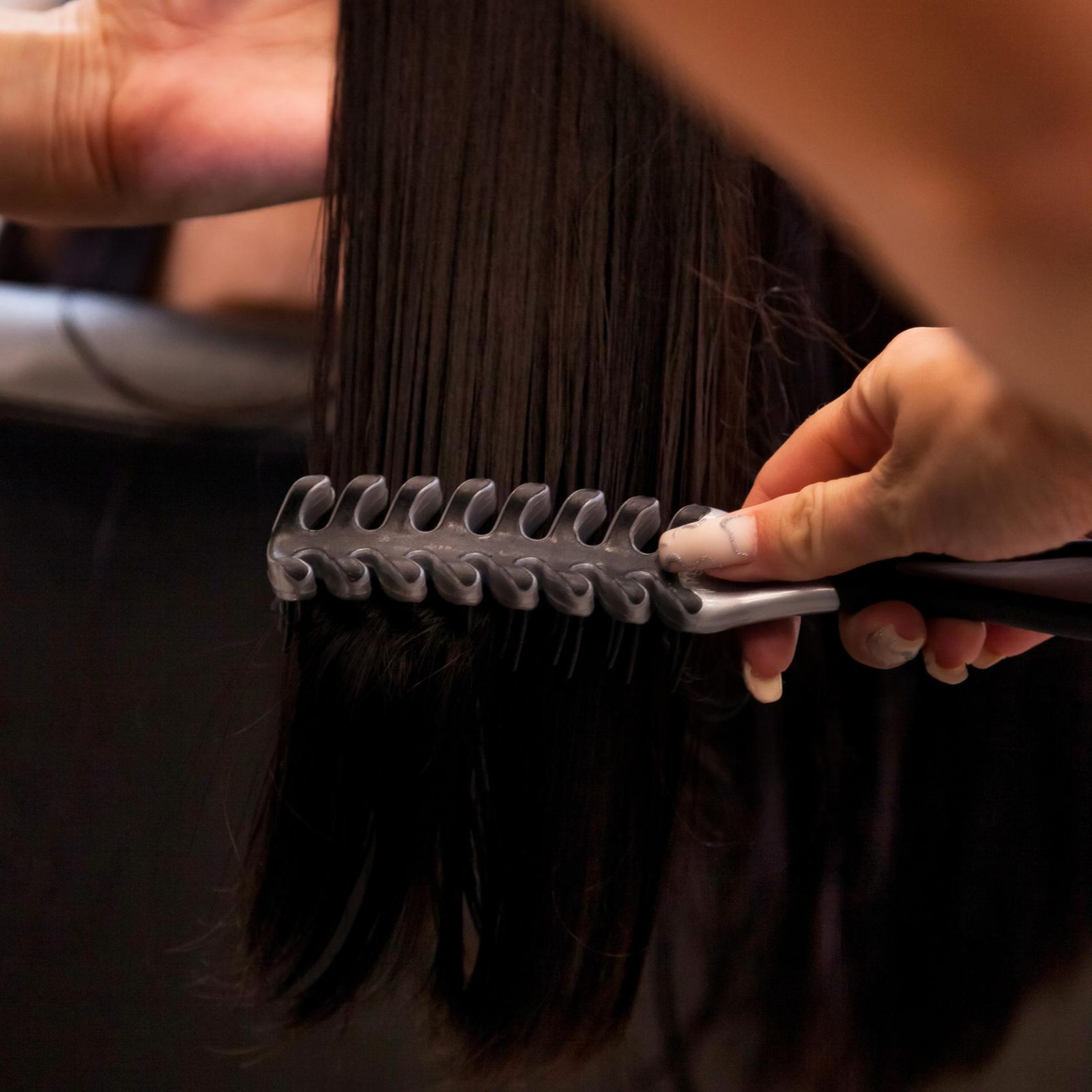 primer plano de manos de un estilista peinado eñ cabello con un peine primer plano de manos de un estilista peinado eñ cabello con un peine